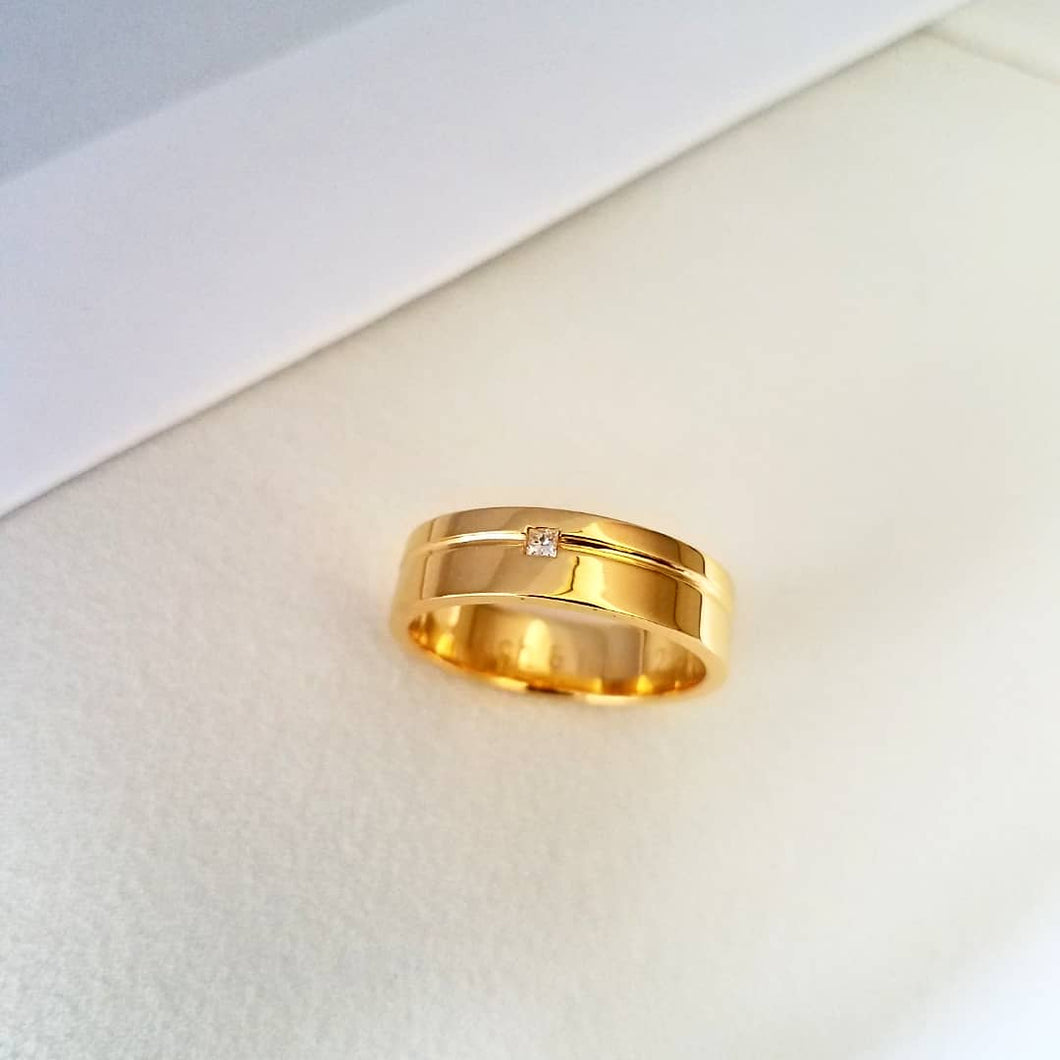An 8mm gold wedding band with a 2mm princess cut diamond as center stone.