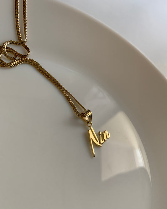 A yellow gold name necklace with the name "Nin".