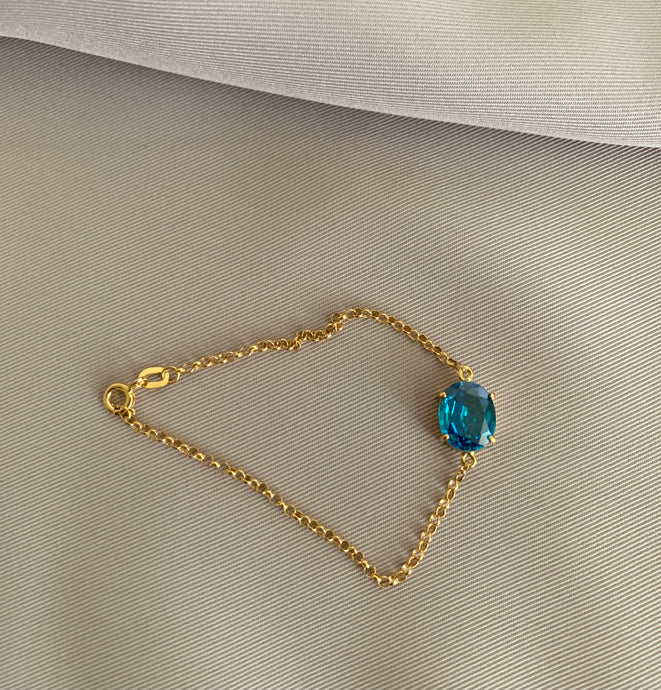 Blue oval topaz gemstone bracelet set in yellow gold.