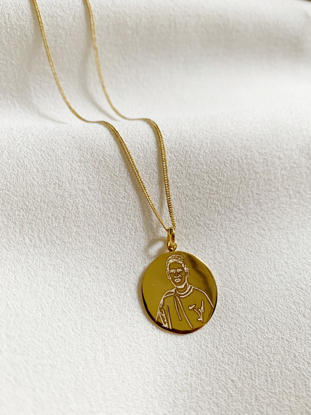 A round pendant with an engraved photo in it. Set in yellow gold.