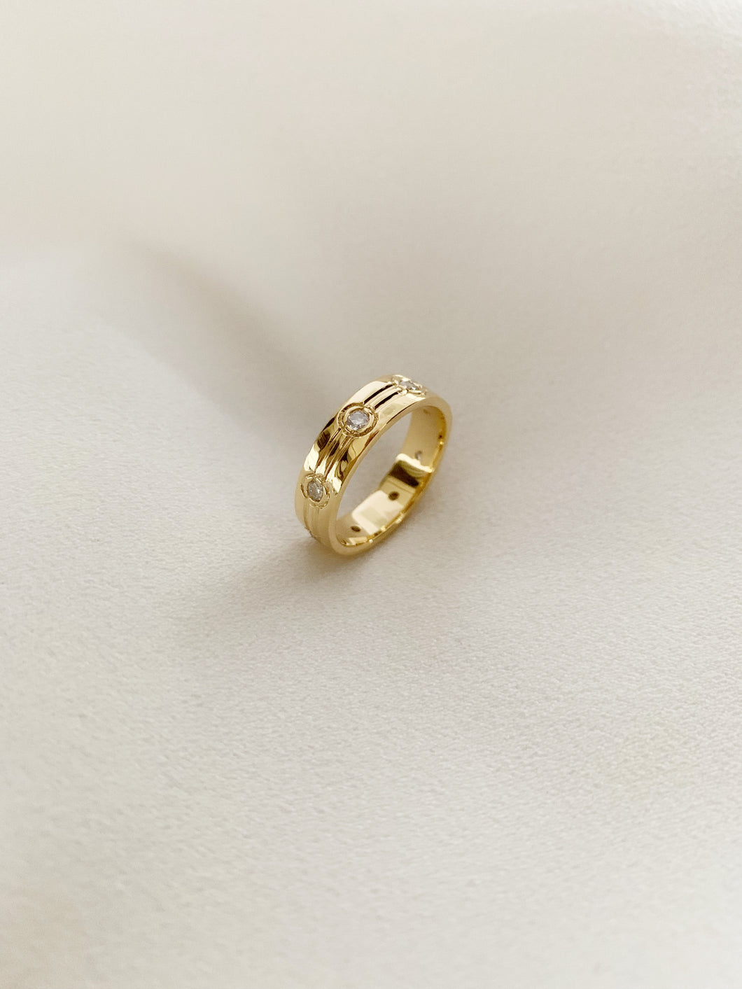 Yellow gold ring with 2 lines in it and small round diamonds around the ring.