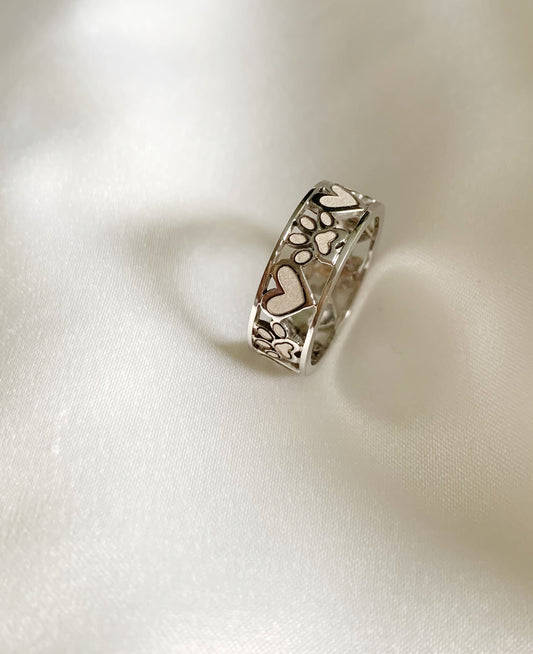 White gold band ring surrounded by alternating hearts and paws arouns it.