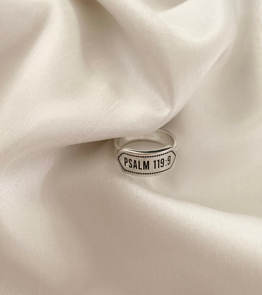 A white gold ring with a "Psalm 119:9" as its center design. 