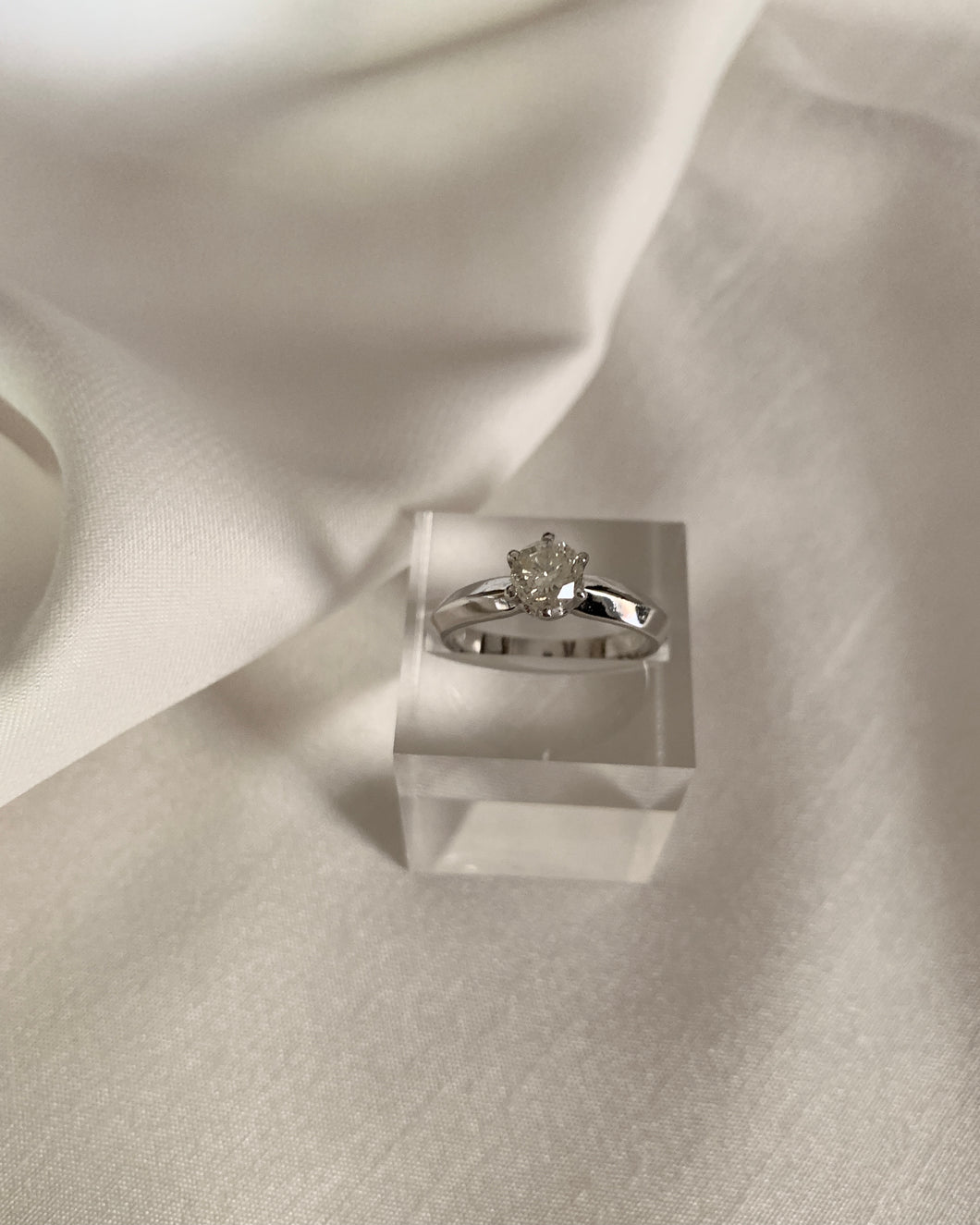 A white gold ring with a knife edge band design with a round diamond as a center stone.
