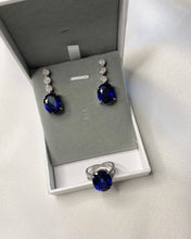 Load image into Gallery viewer, A pair of blue oval sapphires as earrings with 3 round diamonds that makes it into dangling earrings. Paired with an oval blue sapphire ring set in white gold too.
