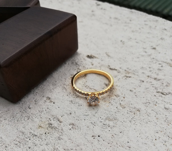 A round diamond set in yellow gold with small, small diamond as the side design of the ring itself.