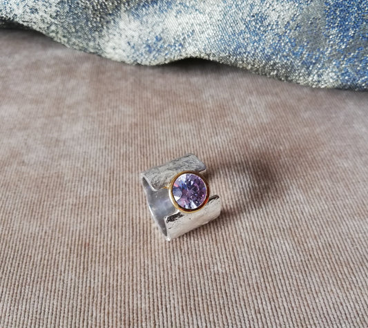 A whitegold feminine band with a purple gemstone as its center stone.