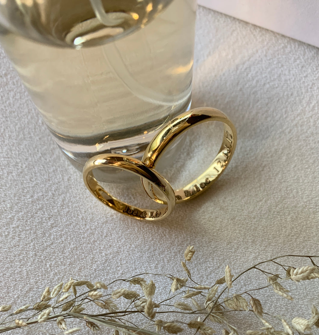 A pair of gold classic wedding rings with name engravements of the couple.