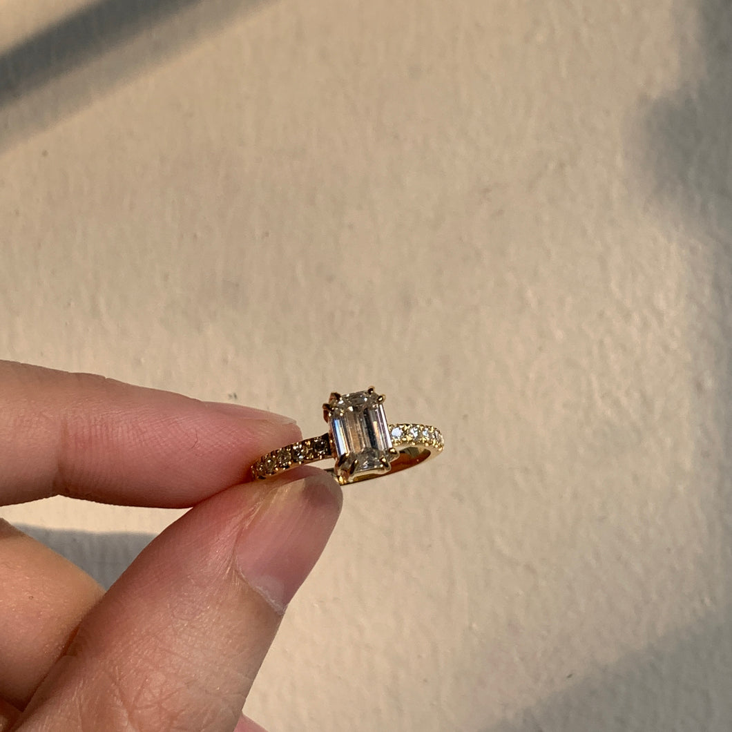 A classic emerald diamond ring with small brilliant diamonds set in yellow gold.