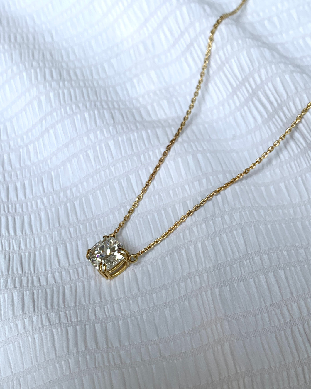 A beautifully set cushion-cut signity on a double prong open basket. Seems floating on an 18k gold classic chain.