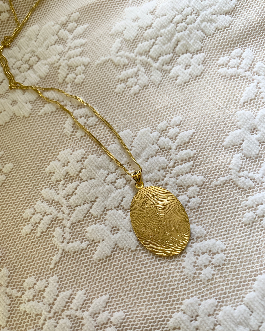 A yellow gold fingerprint or thumbmark pendant. 