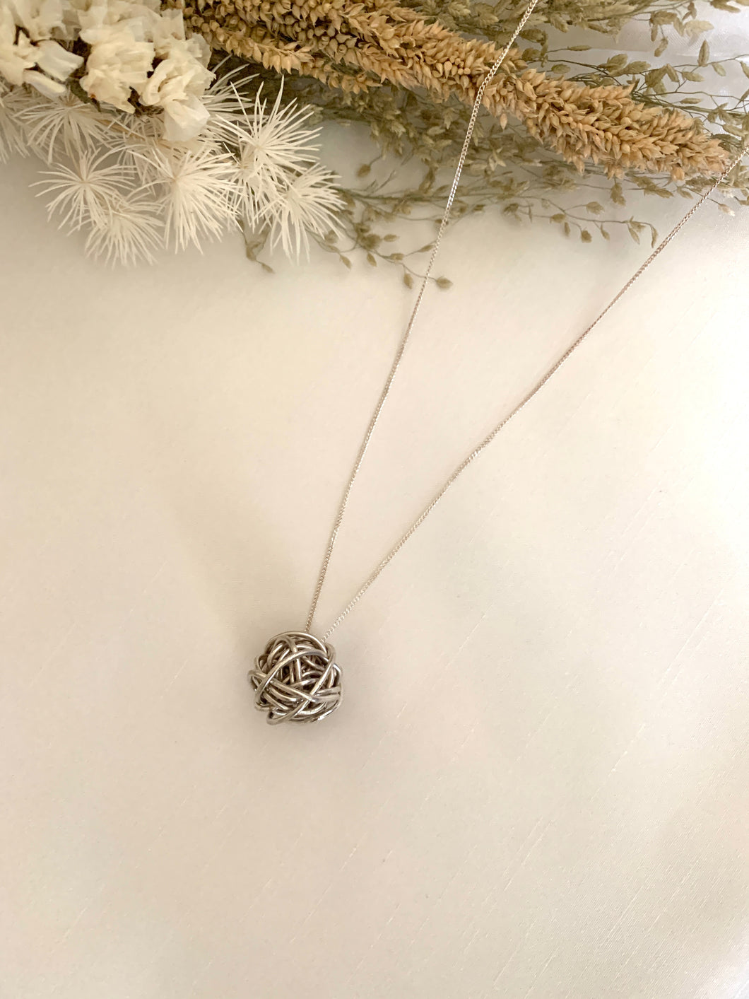 Pendant is a white gold ball of yarn in a white gold chain necklace.
